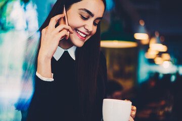 Skilled female copywriter talking on mobile discussing details of task updating application on...