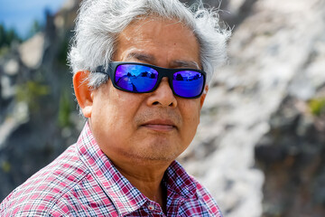 A retired asian man is out on a holiday in beautiful nature. Happy vacation time at Crater Lake, Oregon.