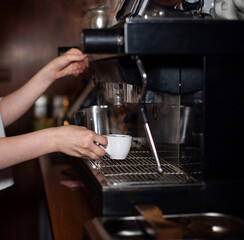 Girl makes espresso in a coffee machine. Barista is making coffee. Coffee shop, restaurant, catering establishment. Close-up hands make a drink