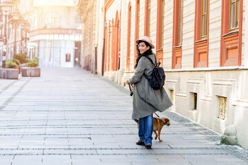 young attractive woman playing with her dog on the city street, lifestyle people concept. Beauty woman with her dog playing outdoors