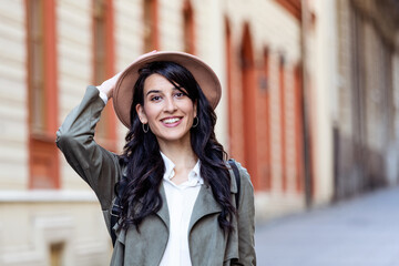 Sunny lifestyle fashion portrait of young stylish hipster woman walking on the street, wearing trendy outfit, hat, travel with backpack.
