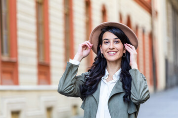 Outdoor portrait of a young beautiful fashionable happy lady posing on a street of the old city. Model wearing a hat. Girl looking up. Female fashion. City lifestyle. Copy space for text