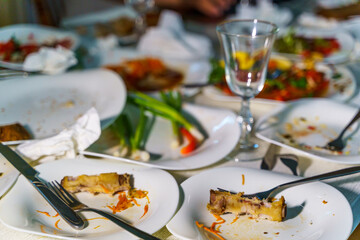 Dishes and glasses are dirty on the table after eating. Empty plates with remnants of food after diner.