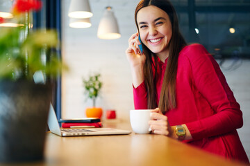 Skilled female copywriter talking on mobile discussing details of task updating application on...