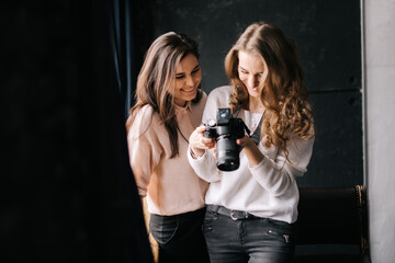 Woman photographer with model looking on camera screen in studio. Concept of creative work in photo studio, backstage job.