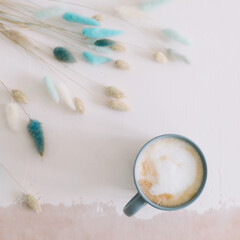 Coffee cup with dried flowers. Breakfast flatlay with big mug of milky cappuccino coffee and flowers. Rustic style. Good morning