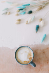 Coffee cup with dried flowers. Breakfast flatlay with big mug of milky cappuccino coffee and flowers. Rustic style. Good morning