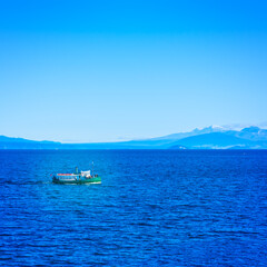 Tourist steamboat in the deep blur waters of Taupo lake with Ruapehu mountains in the background on a beautiful sunny day. North Island Volcanic Plateau, New Zealand