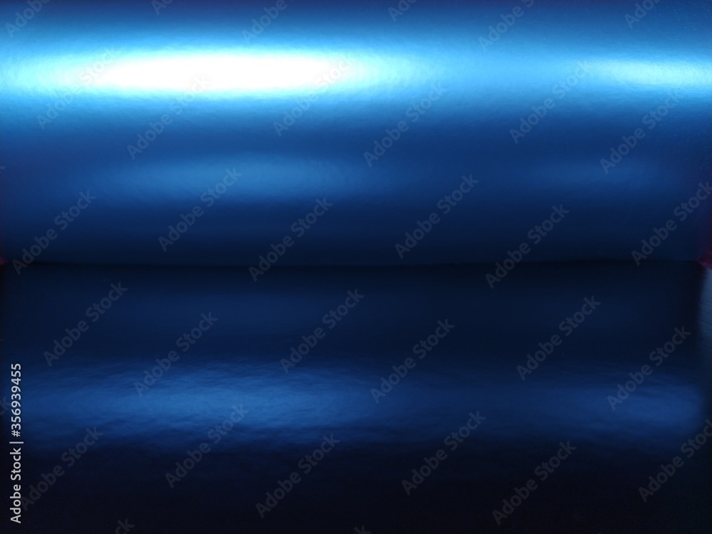 Poster gradient on a blue background. horizontally folded shiny paper or foil with overflow and highlights.