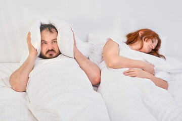 The man covered his head with a pillow due to his wife's snoring. Trouble sleeping in the family....