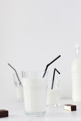 Fresh milk in a glass with black straws, chocolate candies with souffle, tasty healthy drink