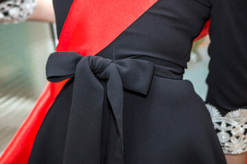 Red ribbon and a schoolgirl's belt tied with a bow close-up. Elements of strict school uniform at the graduation and the last call.