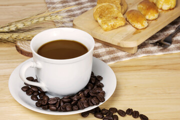 Coffee cup with coffee beans on wooden table.