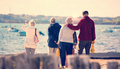 Groupe de retraités en bord de mer regardant l'horizon.