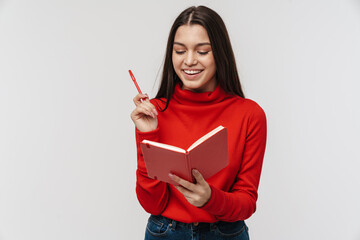 Photo of happy caucasian woman smiling and making notes in planner