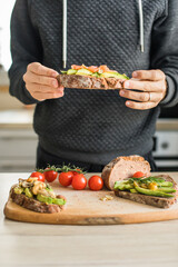 Close up of man making plate with avocado toast as fresh snack, day light. 