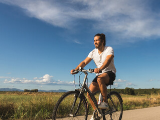 Obraz premium Young man on a bicycle on a country road wearing a mask