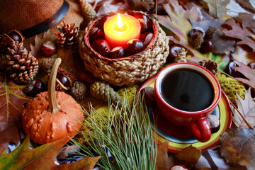 Obraz na płótnie Canvas Autumn decoration, table with autumn leaves, cones, a pumpkin, a candle and a coffee cup, close up