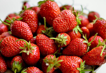 A lot of red, juicy strawberries on a plate. Red berries on a white background. Natural eco-product.