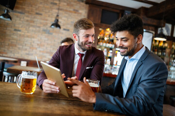 Happy young businessmen in suits are smiling and talking in a restaurant