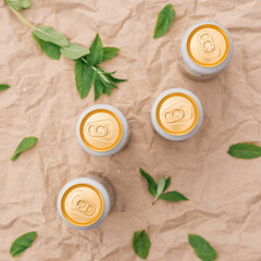 Four closed beer or soda gold aluminum cans, on a background of crumpled craft paper with mint leaves, top view, isolated, nobody. The concept of beer advertising.