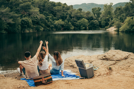Friends toasting at a lake.