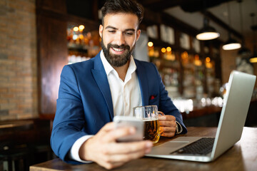 Handsome young business man, blogger or remote working with laptop in bar