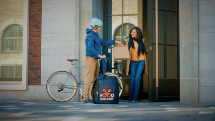 Happy Food Delivery Man Wearing Thermal Backpack Rides Bike to Deliver Restaurant Order to a...