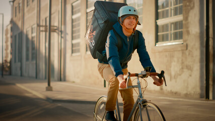Happy Food Delivery Courier Wearing Thermal Backpack Rides a Bike on the Road To Deliver Orders for...