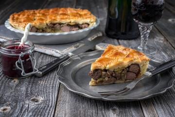 Rustic Venison Pie with cranberry relish as close-up on a pewter plate