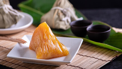 Alkaline rice dumpling zongzi - Traditional sweet Chinese crystal food on a plate to eat for Dragon Boat Duanwu Festival celebration concept, close up.