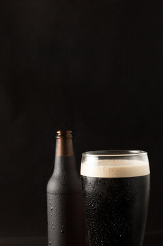 bottle and glass of cold beer with a red plate on a black background