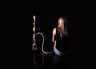 girl, woman sitting on a black background sideways hiding her face next to a hookah