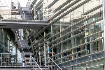 A fragment of a modern corporate building and an external stairwell. The structure is made of glass and concrete.