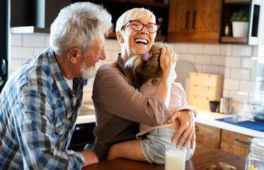 Happy grandparents playing with their little cute granddaughter