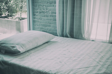 Fototapeta na wymiar white pillow on bed beside see through window curtai