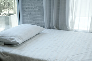 white pillow on bed beside see through window curtai