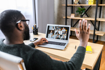 Confident African-American male worker talking online with coworkers, back view of black guy is waving hello to many people on video screen. Remote work, virtual meeting - Powered by Adobe