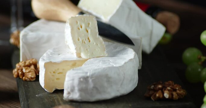 Slices of Camembert cheese on cutting Board slowly rotate.