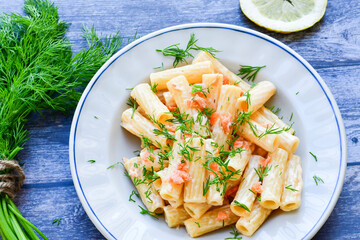  Italian home made  macaroni pasta with smoked salmon , creamy sauce and fresh dill on wooden background
