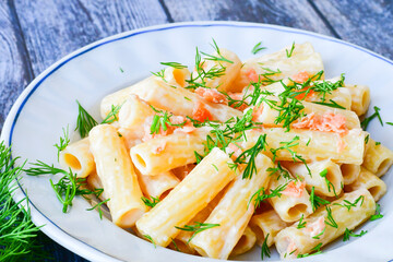  Italian home made  macaroni pasta with smoked salmon , creamy sauce and fresh dill on wooden background