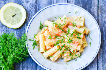  Italian home made  macaroni pasta with smoked salmon , creamy sauce and fresh dill on wooden background