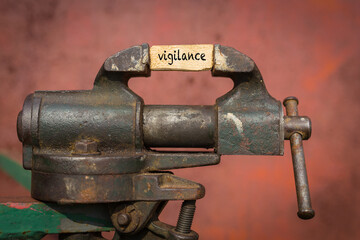 Vice grip tool squeezing a plank with the word vigilance