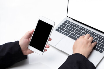 Fat businesswoman's hand holding smartphone and using laptop to working her job on white table at office