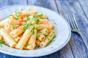  Italian home made  macaroni pasta with smoked salmon , creamy sauce and fresh dill on wooden background