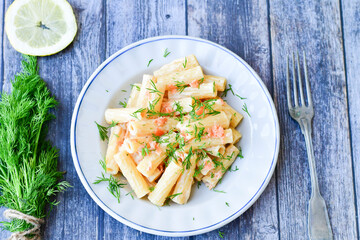  Italian home made  macaroni pasta with smoked salmon , creamy sauce and fresh dill on wooden background