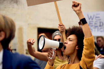 Yung black woman shouting through megaphone on anti-racism demonstrations. - obrazy, fototapety, plakaty