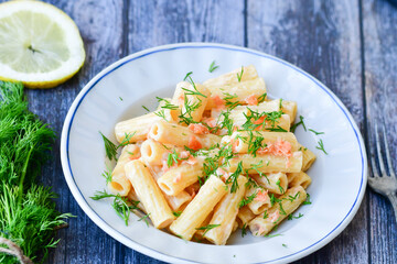  Italian home made  macaroni pasta with smoked salmon , creamy sauce and fresh dill on wooden background