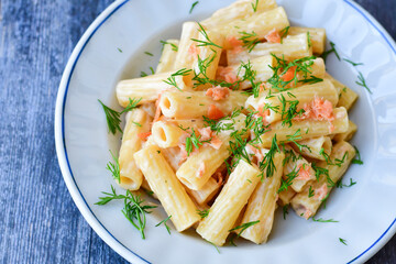  Italian home made  macaroni pasta with smoked salmon , creamy sauce and fresh dill on wooden background