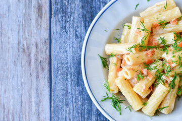  Italian home made  macaroni pasta with smoked salmon , creamy sauce and fresh dill on wooden background